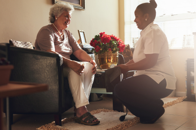 caregiver assisting a senior woman on a couch