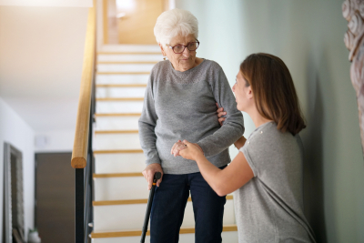 caregiver helping a senior woman get down the stairs